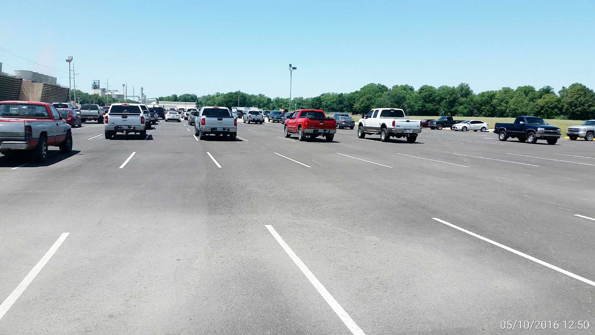 Wide parking lot with several parked cars under a clear blue sky