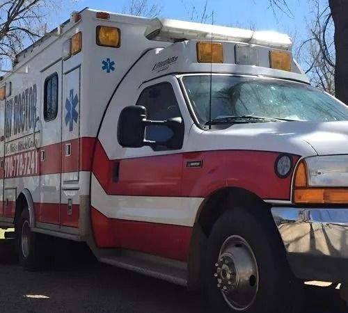 A red and white ambulance is parked on the side of the road