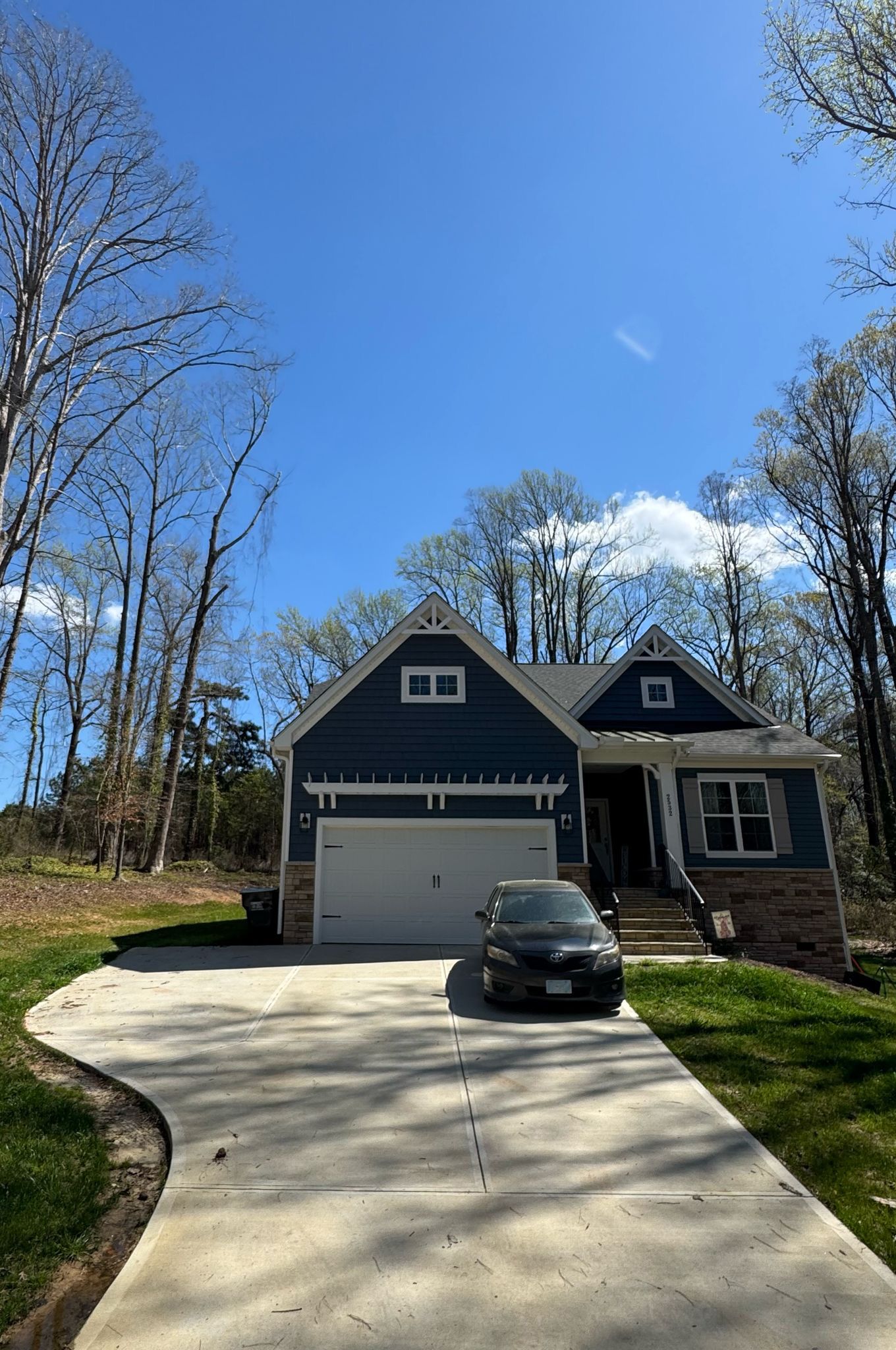 A car is parked in front of a blue house.