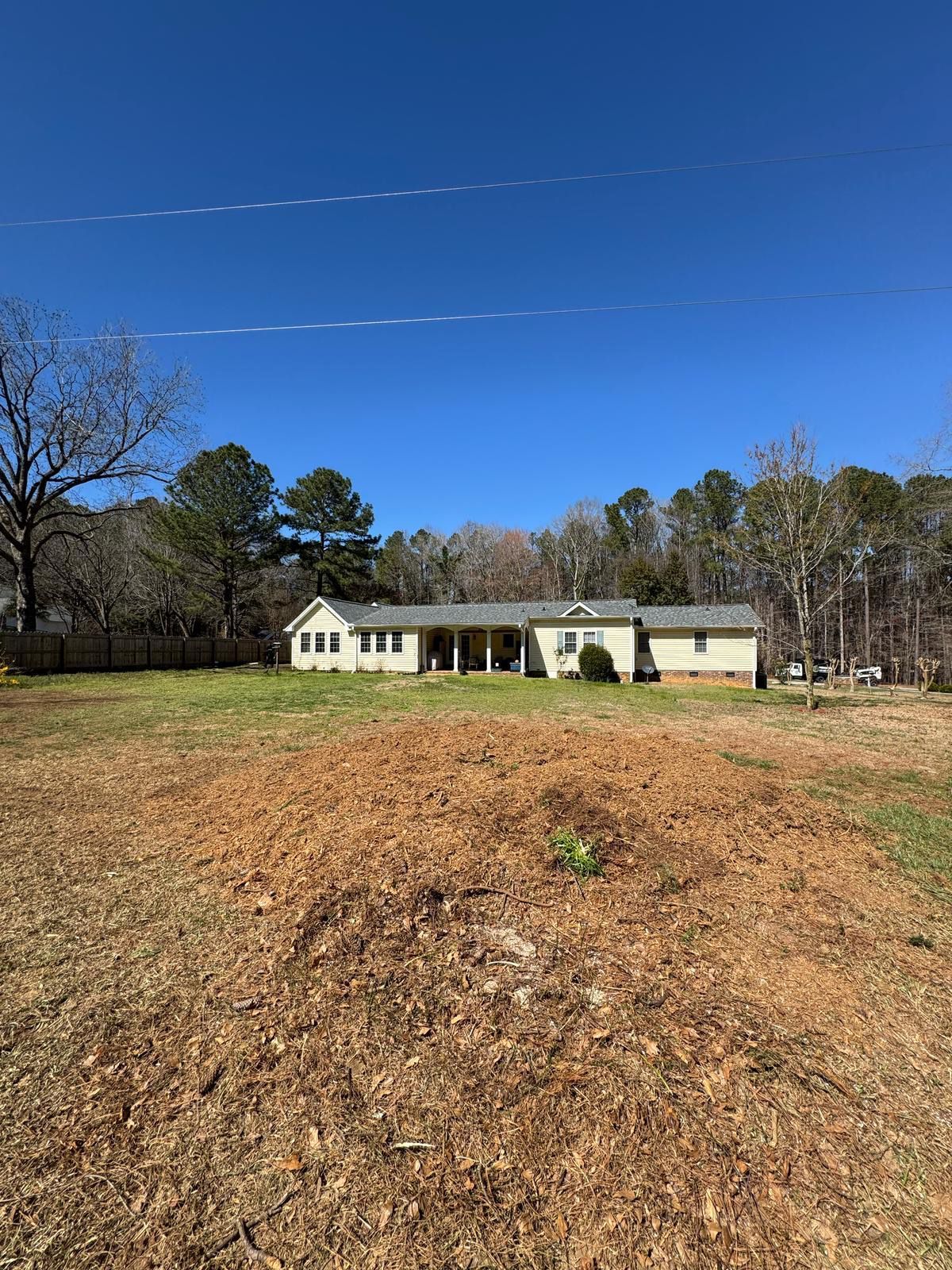 A house is sitting in the middle of a grassy field surrounded by trees.