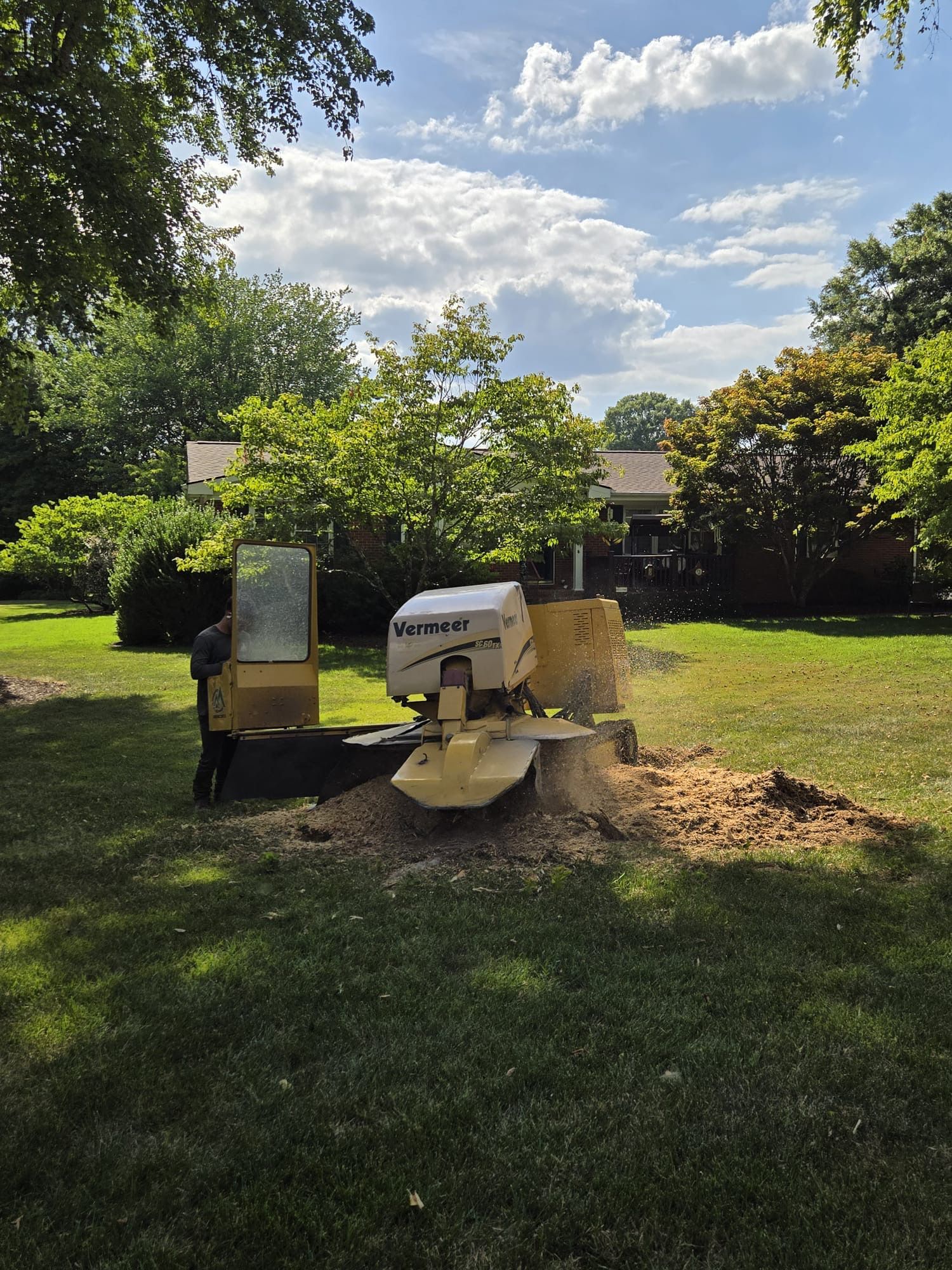 A stump grinder is sitting in the middle of a lush green field.