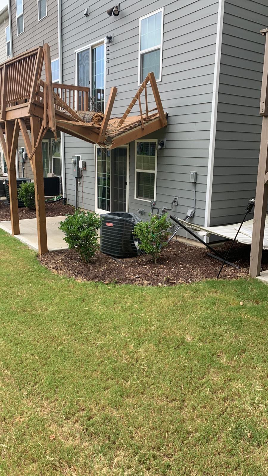 A house with a deck and a lawn in front of it.