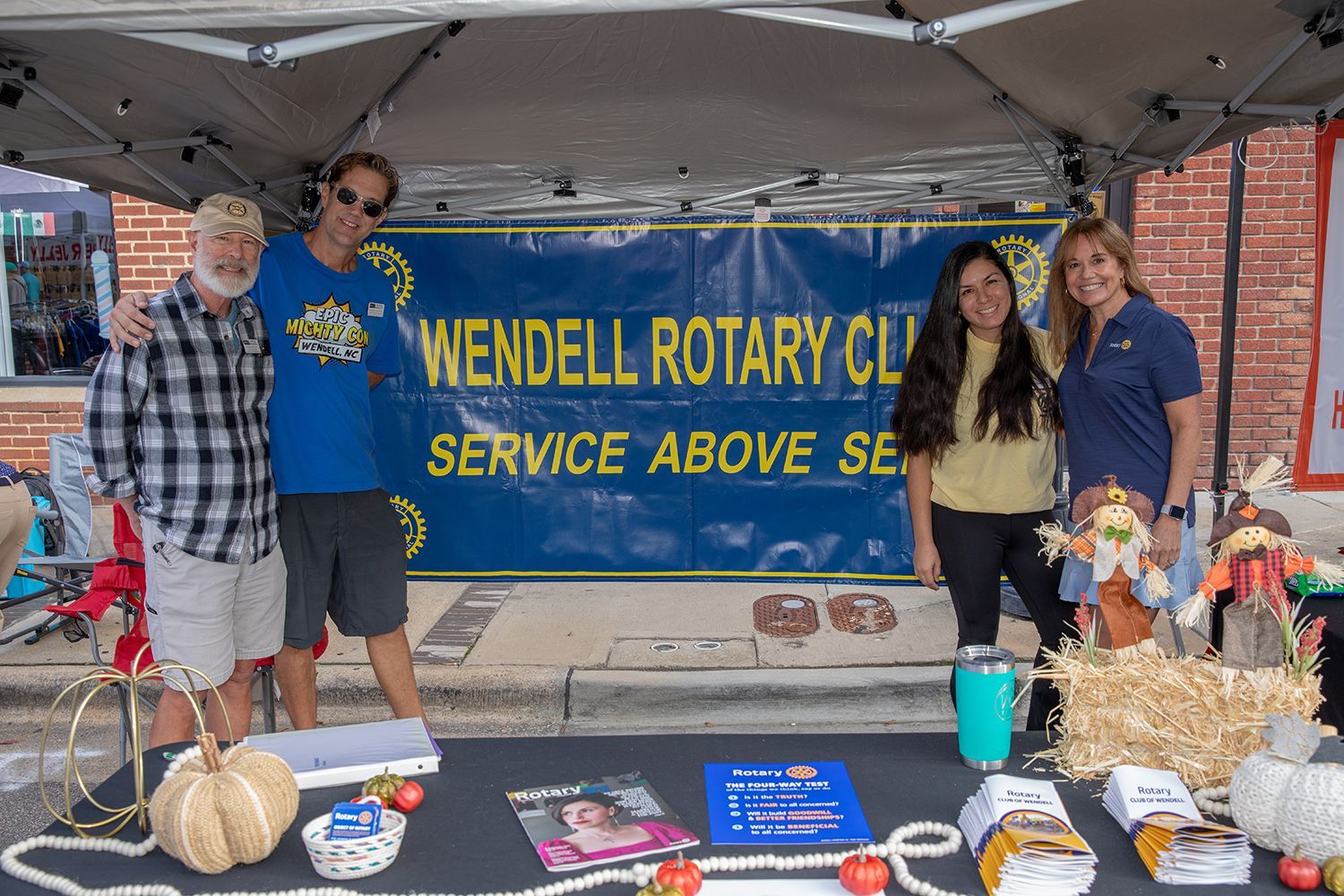A group of people standing around a table under a tent.