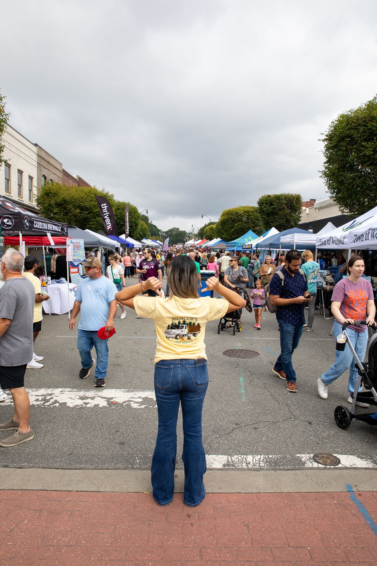 A woman is standing in front of a crowd of people at a street festival.