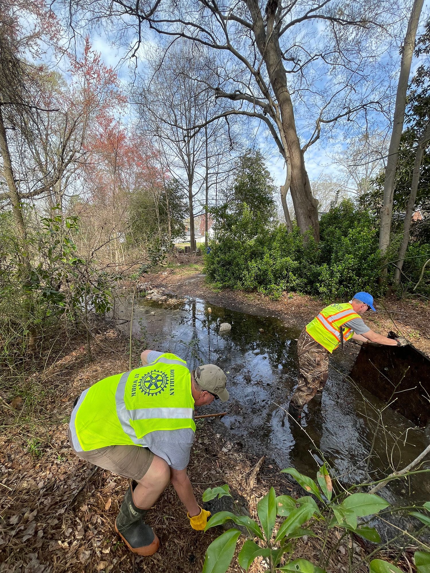 Two men are kneeling in a puddle of water.