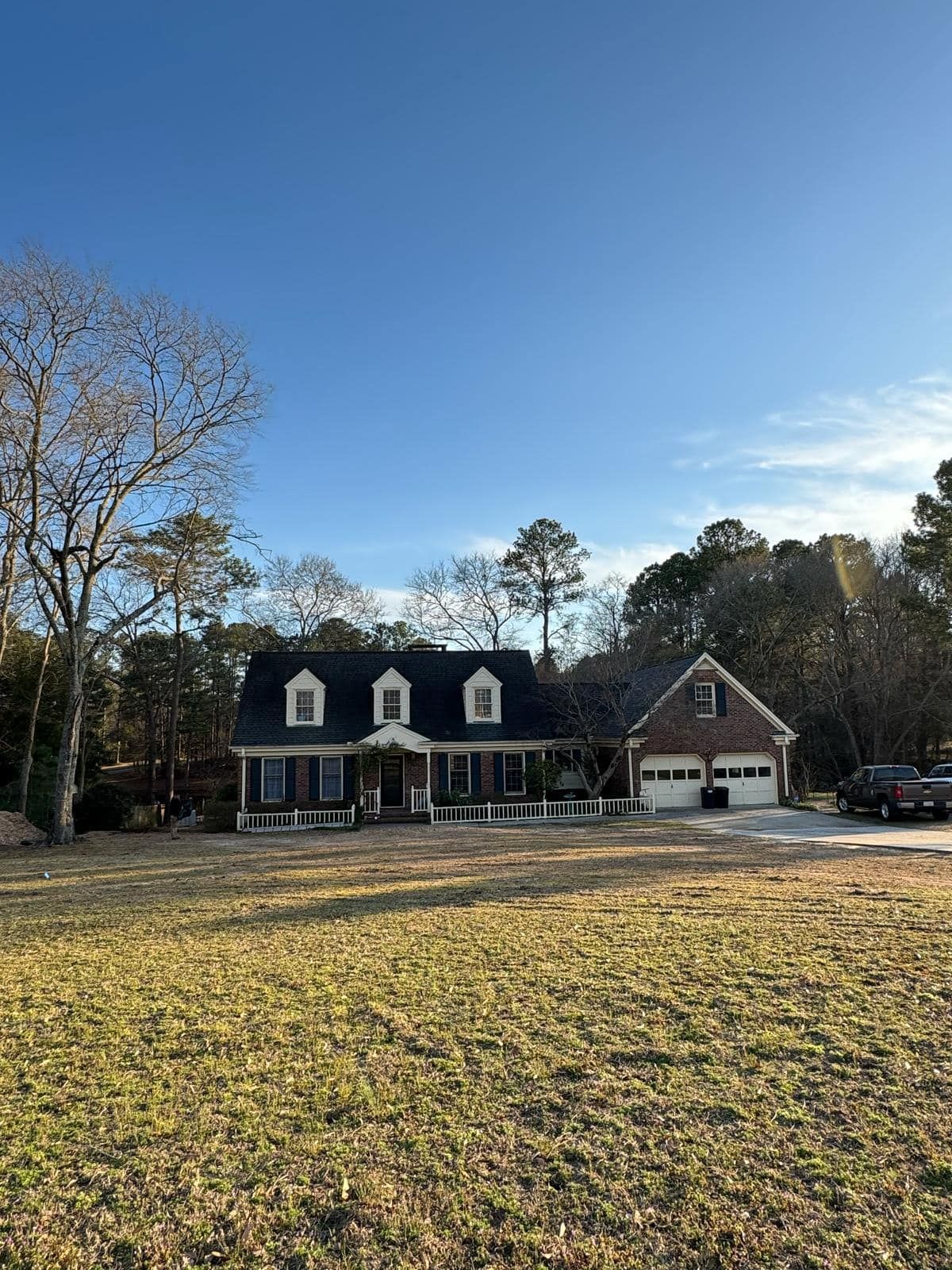 A large house with a black roof is sitting on top of a lush green field.