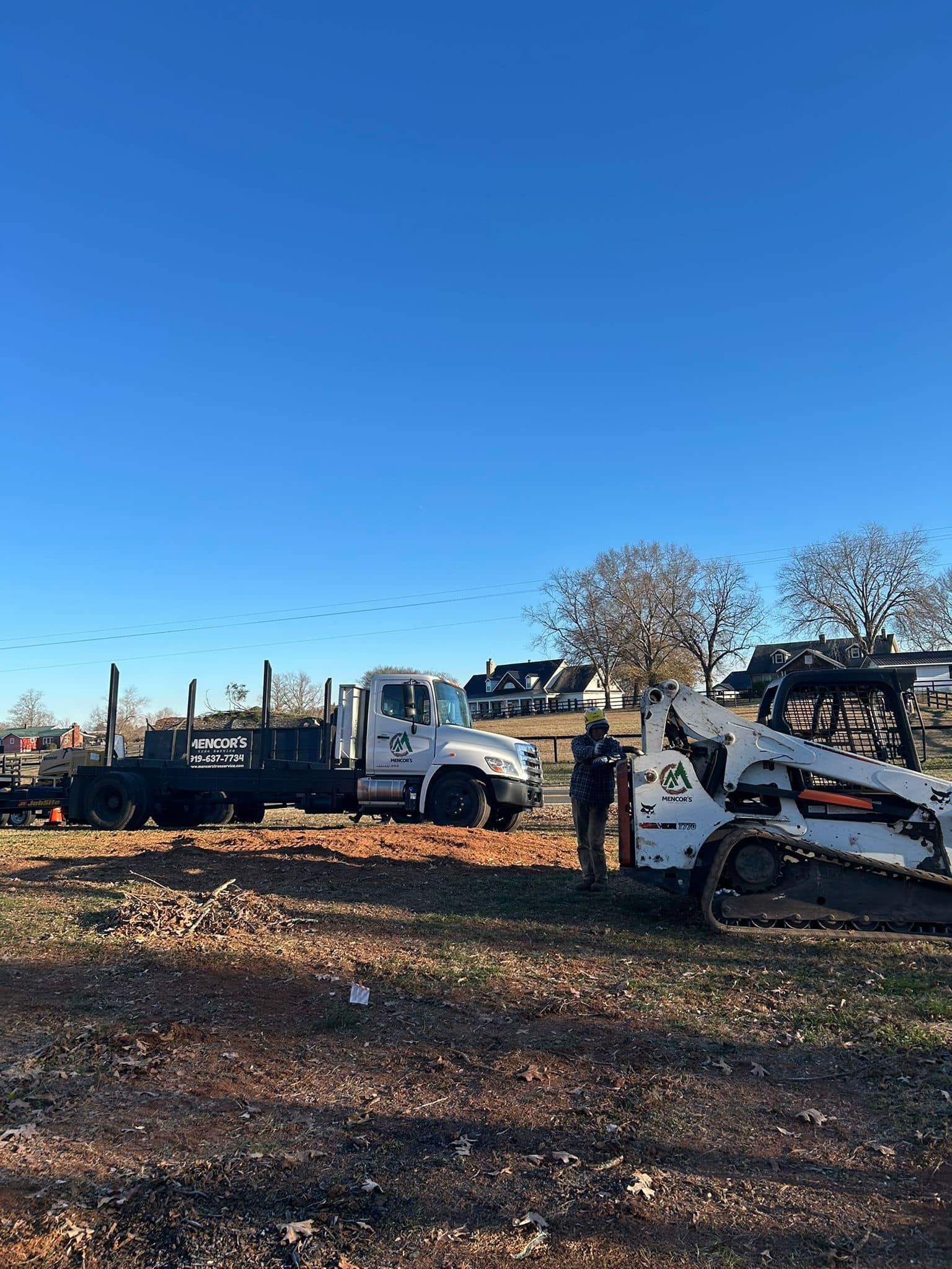 A bulldozer is parked next to a truck in a dirt field.
