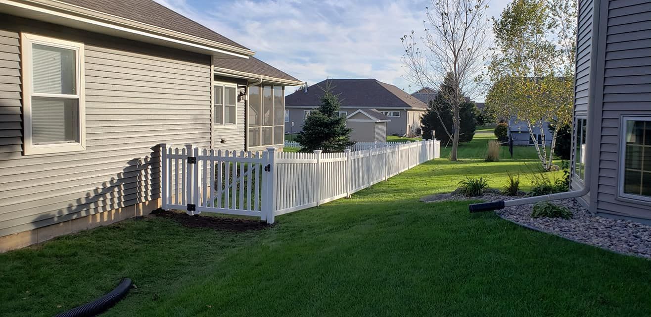 A white picket fence is in the backyard of a house.