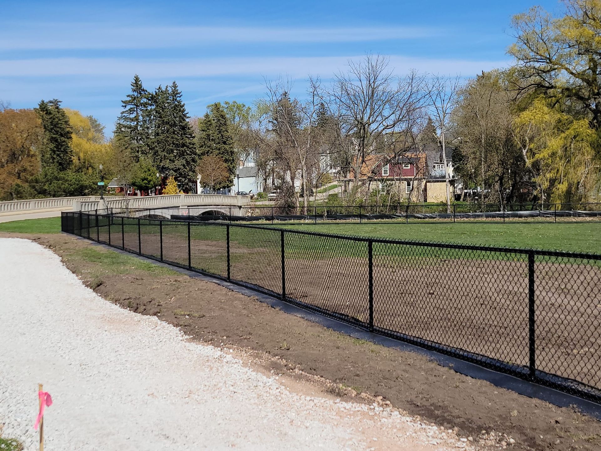 A chain link fence surrounds a field in a park.