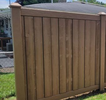 A wooden fence surrounds a patio area with a table and chairs.