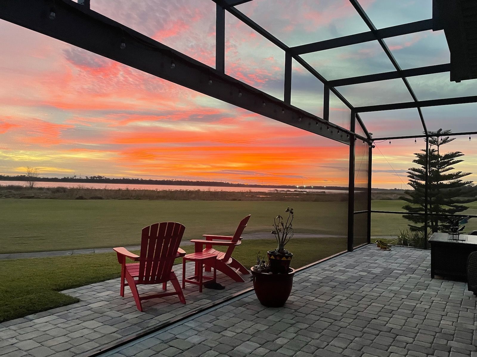 A screened in porch with a couch , chairs , and a coffee table.
