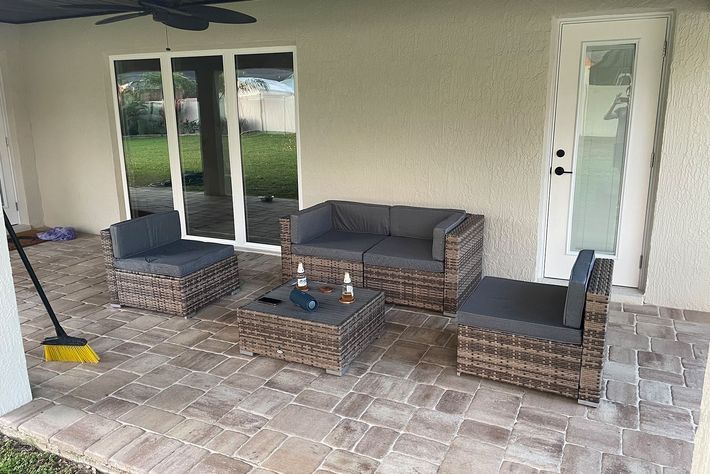 A patio with wicker furniture and a broom.