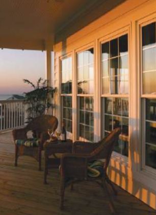 A porch with chairs and a table with a view of the ocean