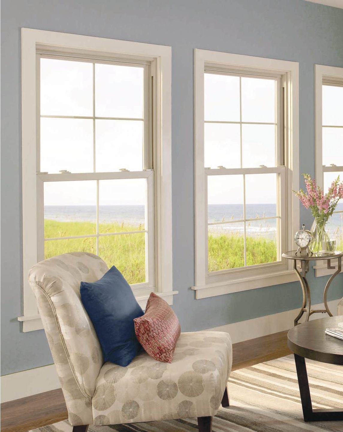 A living room with a chair a table and two windows