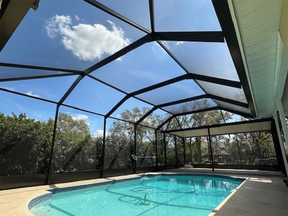 Pool enclosure with blue water, clear sky, and black framing.