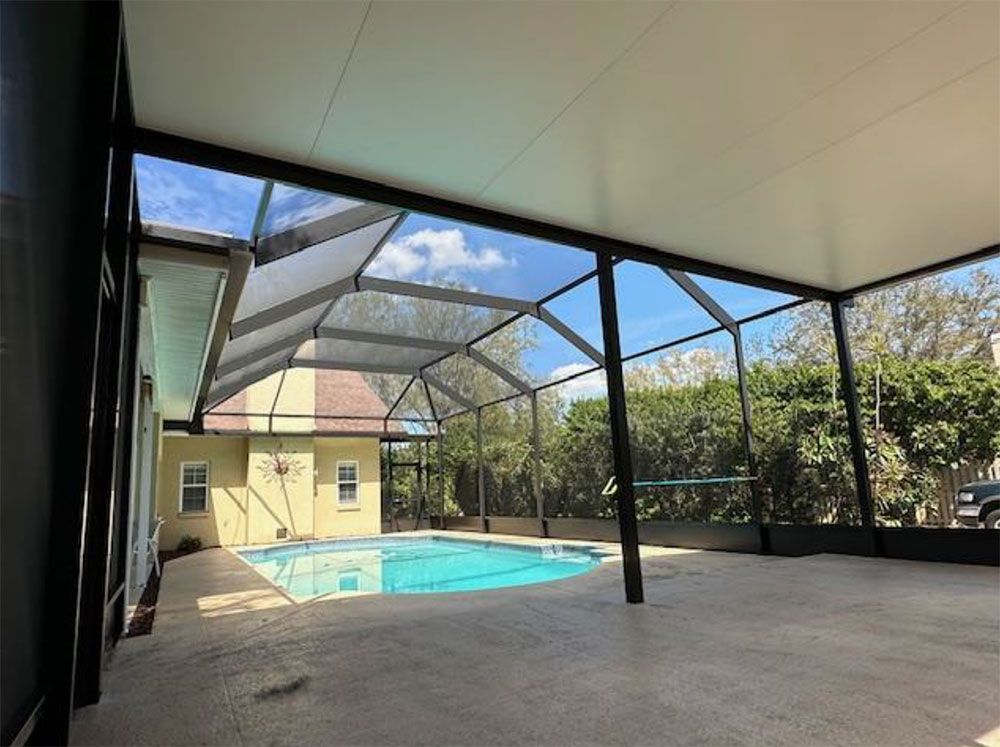 Pool area with screened enclosure, blue water, sunny day.