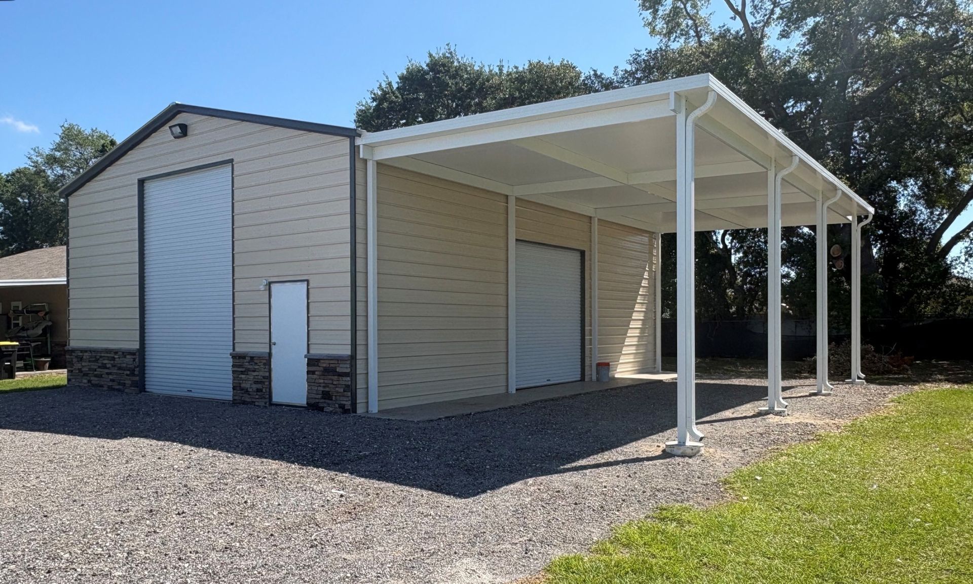 Small beige building with a white metal canopy and gravel ground outside