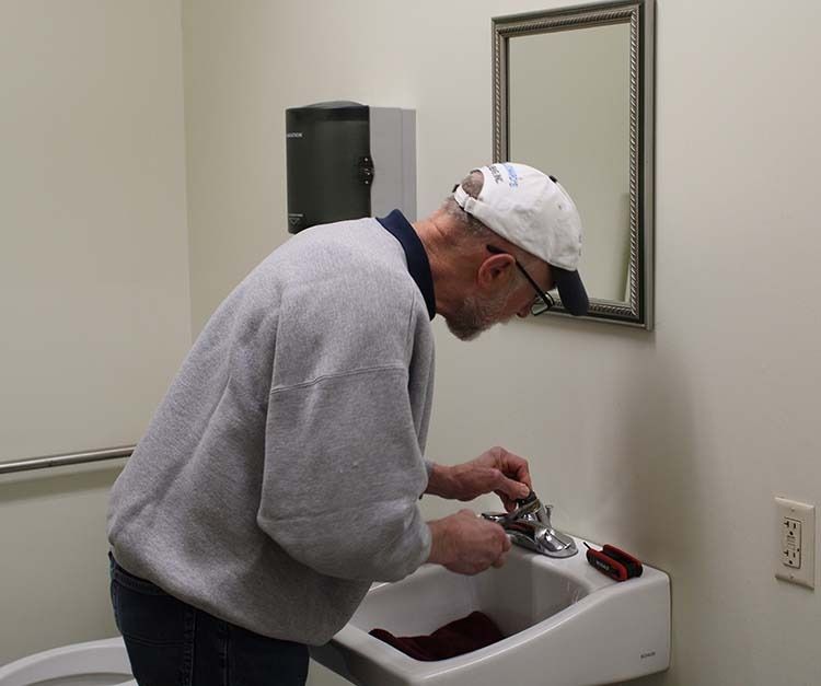 a man is fixing a sink in a bathroom
