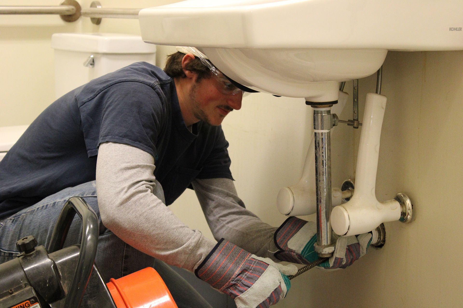 A man is fixing a sink in a bathroom.