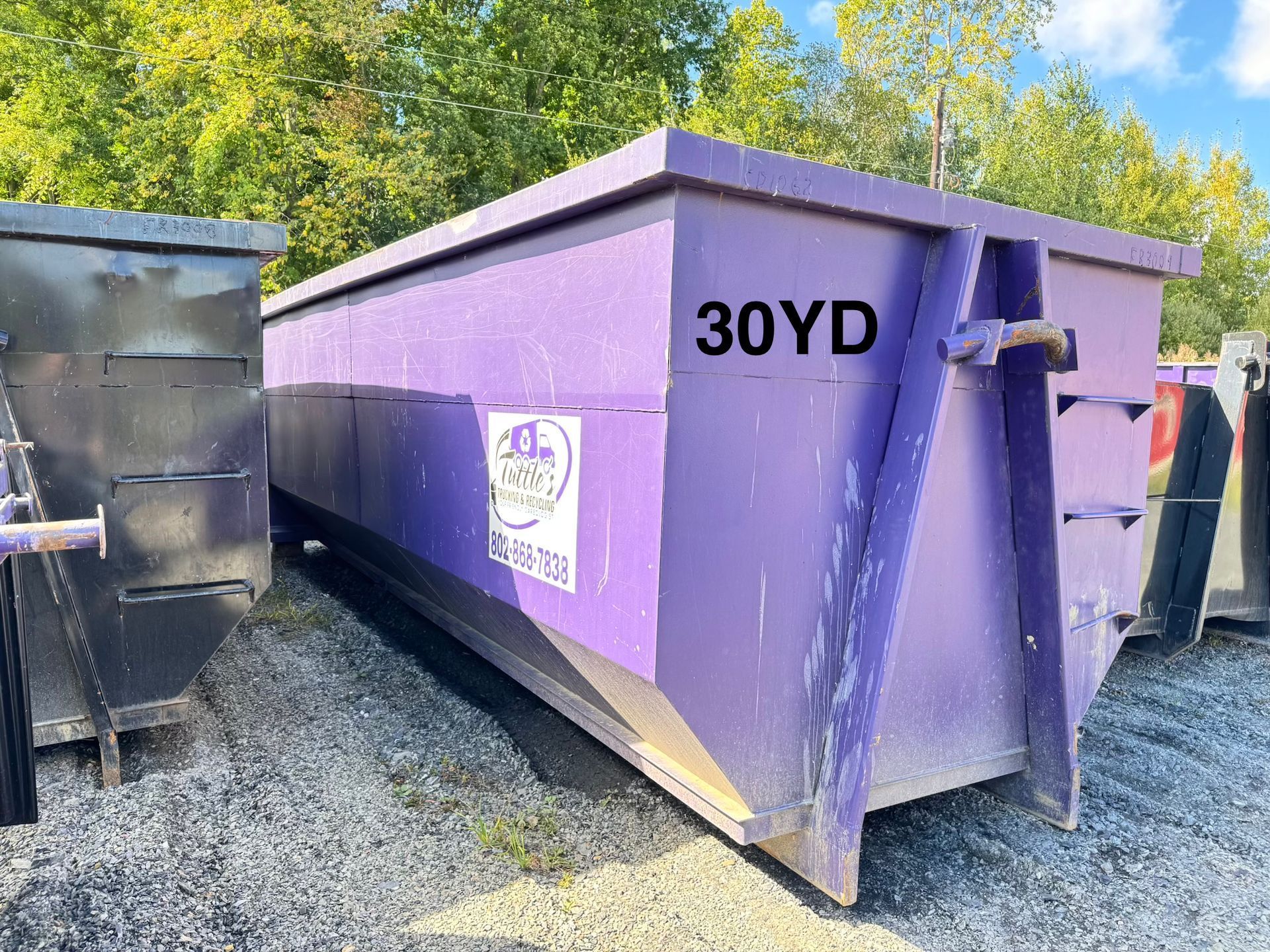 a purple 30-yard dumpster outdoors on gravel