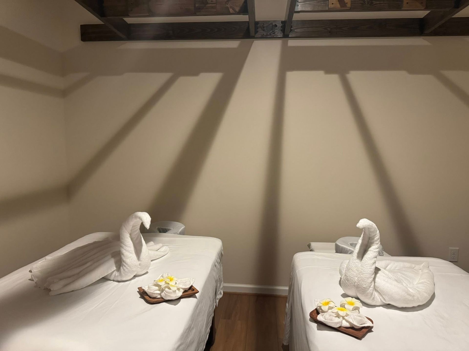 Two massage tables with swan-shaped towels and floral arrangements in a spa setting.