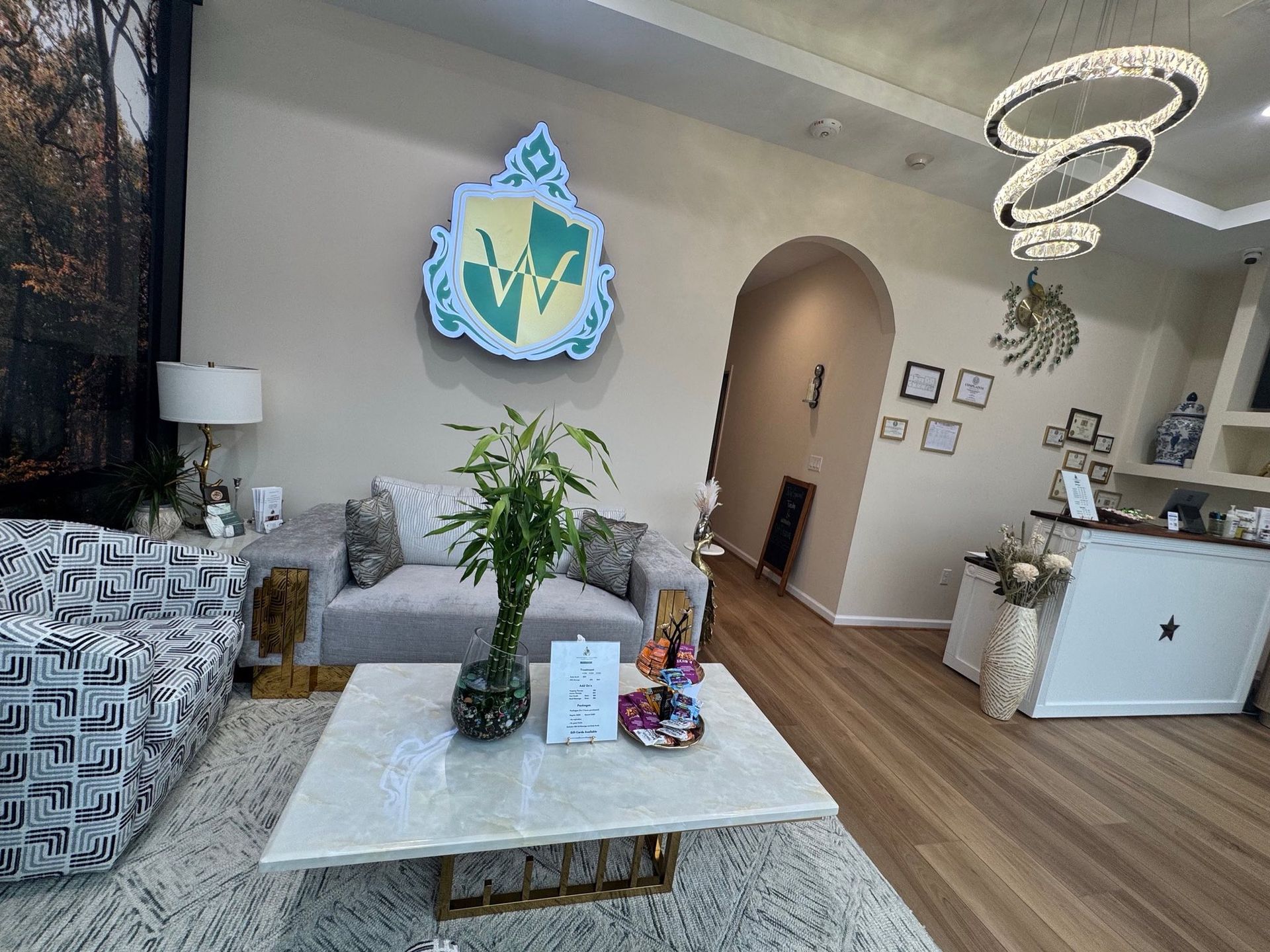 A light-filled reception area with modern furniture, art, and a decorative emblem on the wall.