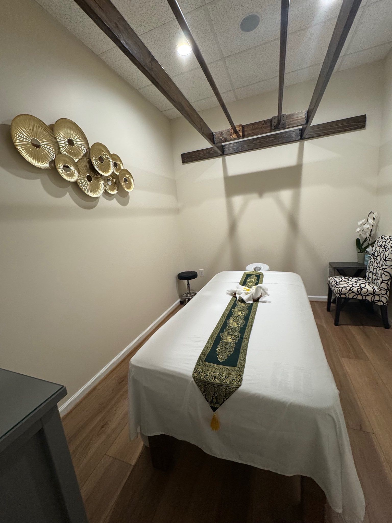 Massage room with a bed, decorations, and chair.