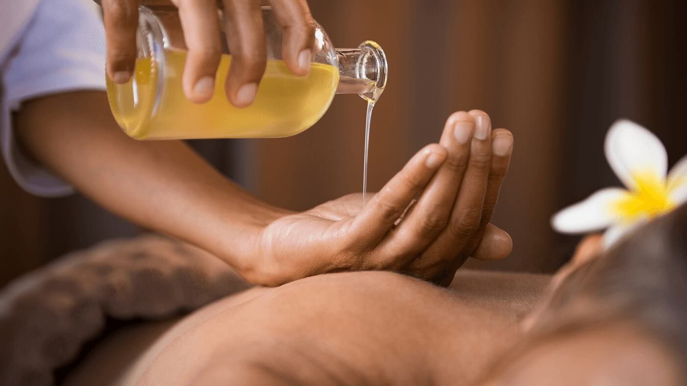 Hands pouring oil from a bottle onto another person's hand, massage therapy.