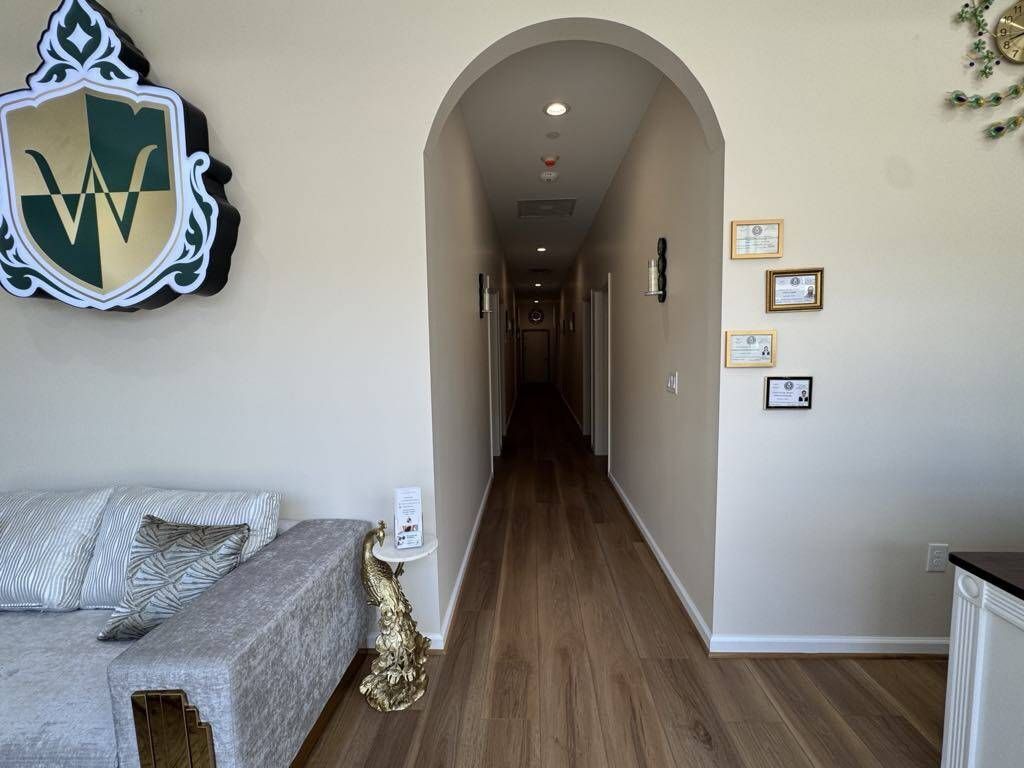 Hallway with archway entrance, wooden floors, framed pictures, and ornate decoration.