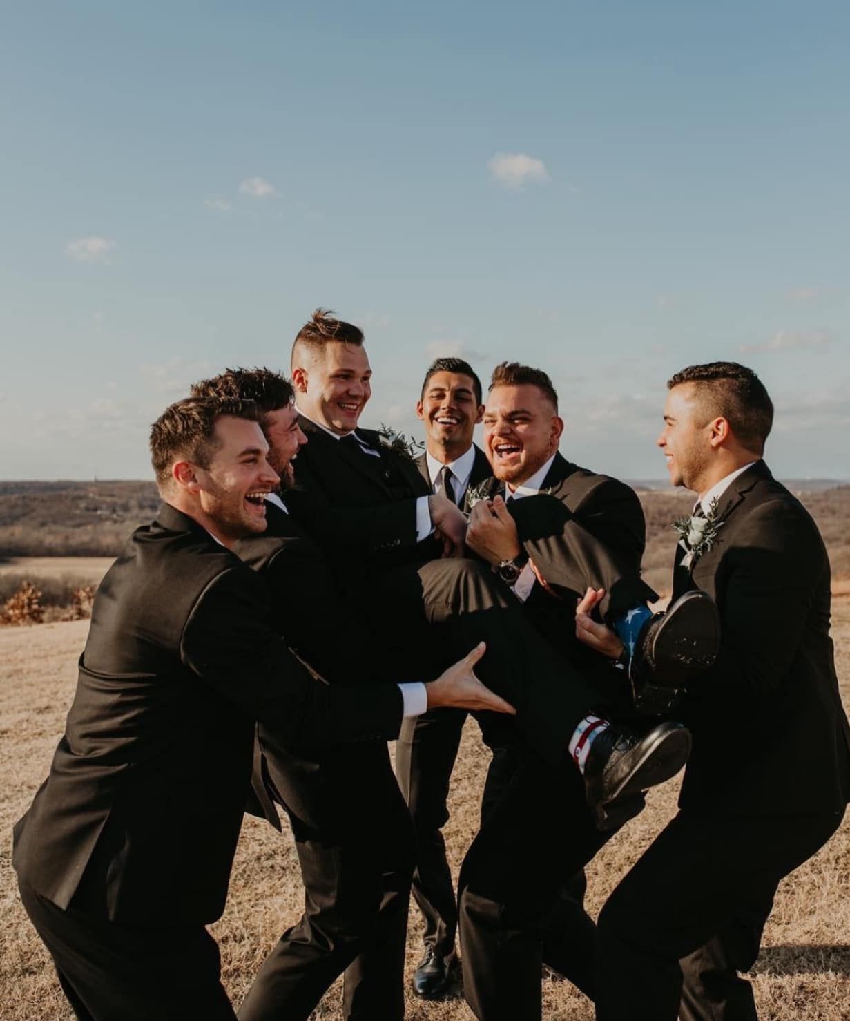 A group of men in suits are playing with each other in a field.