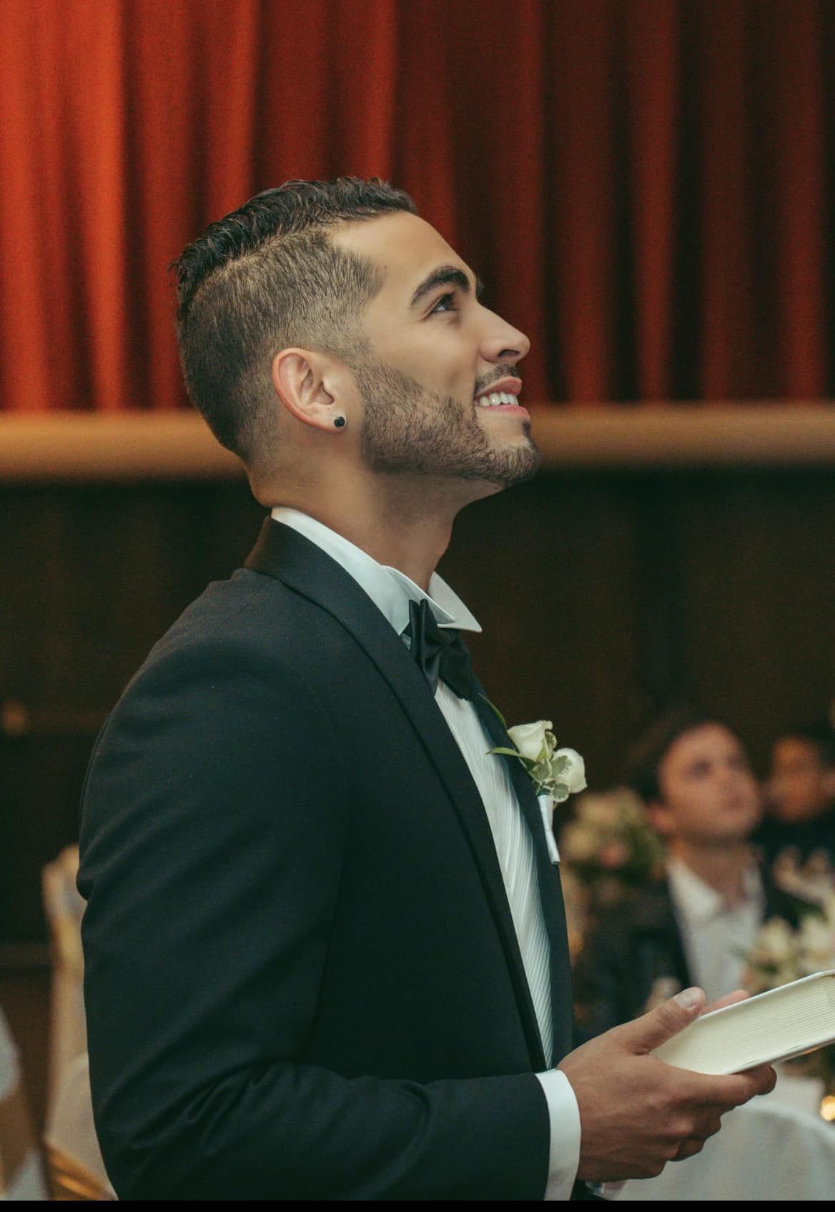 A man in a tuxedo is holding a plate and smiling