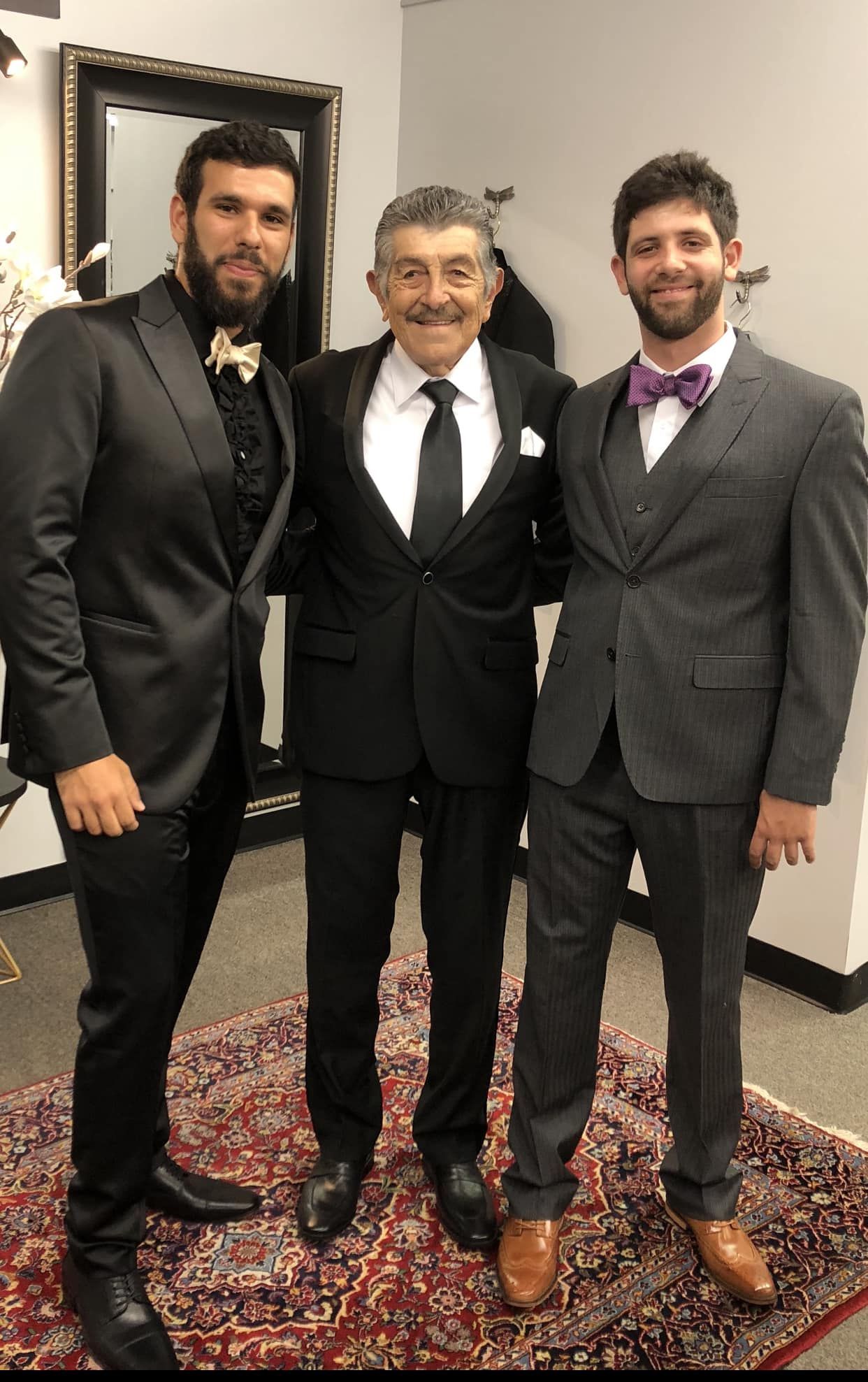 Three men in suits and bow ties are posing for a picture.