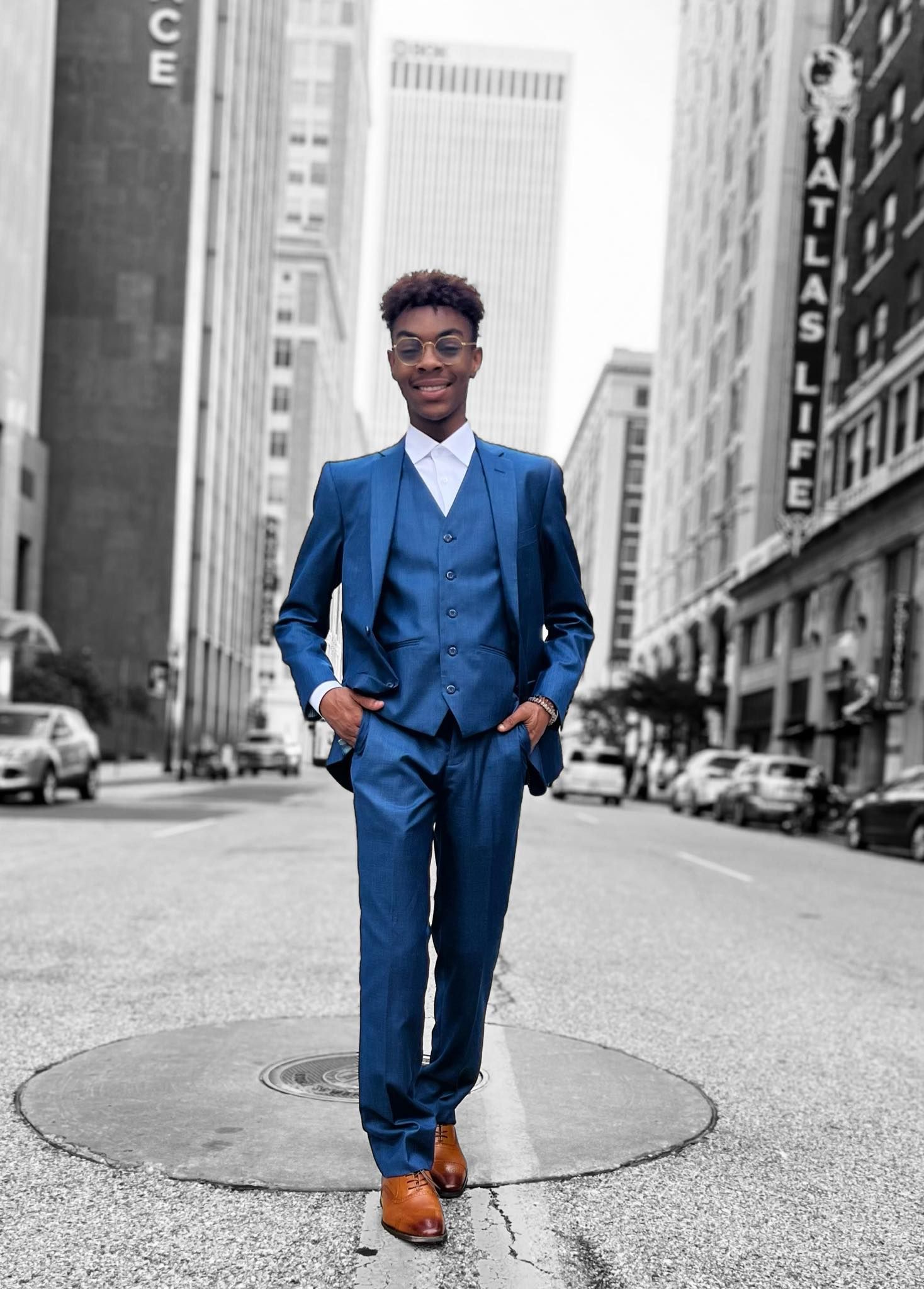 A man in a blue suit is standing on a city street.
