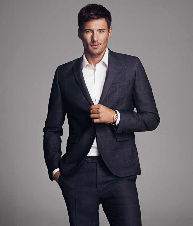 A man in a suit is standing with his hands in his pockets