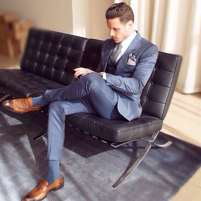A man in a suit is sitting on a chair with his legs crossed