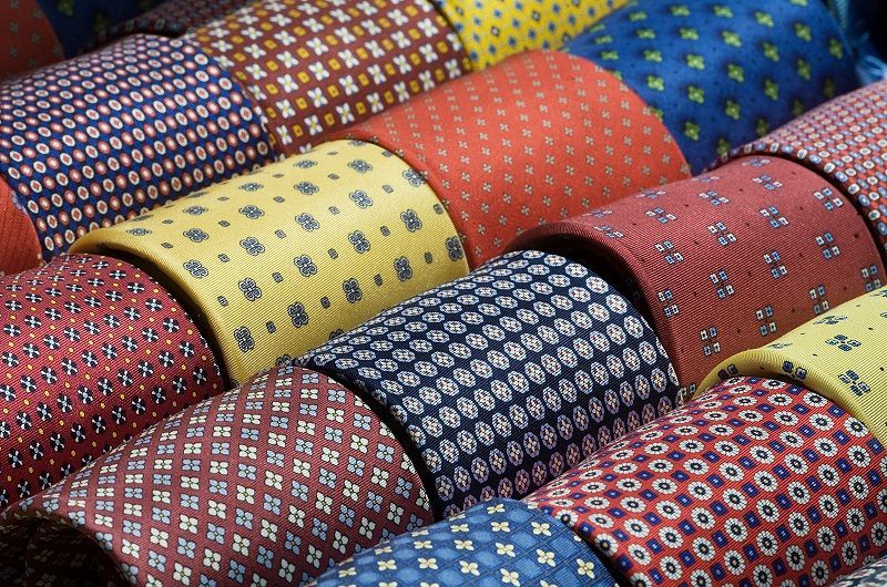 A bunch of different colored ties are stacked on top of each other