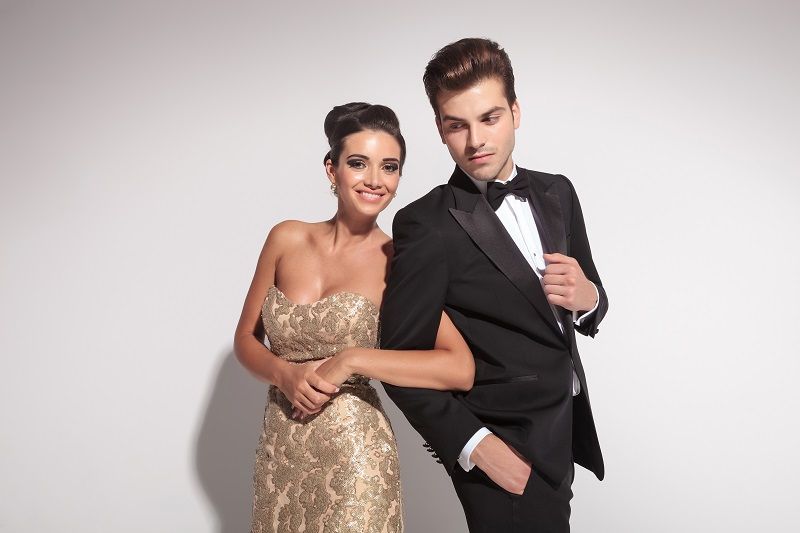 A man in a tuxedo and a woman in a dress are posing for a picture.
