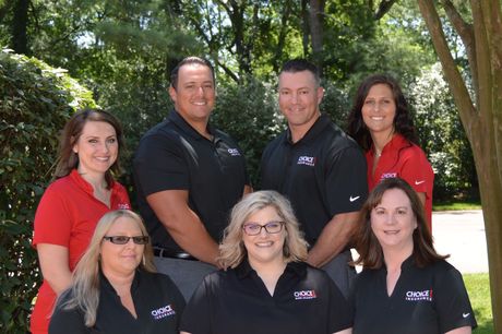 A group of people are posing for a picture in front of trees.