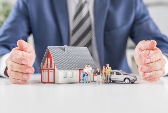 A man is holding a model of a house and a car.