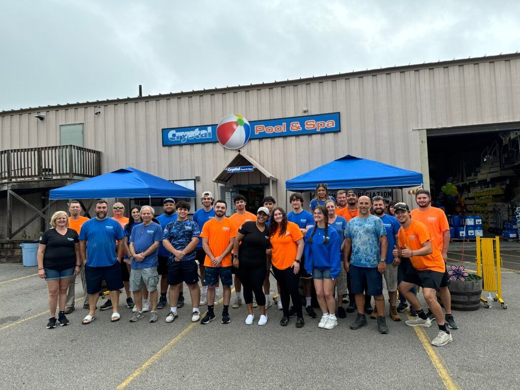 Group of people in blue and orange shirts posing in front of a store with a beach ball.