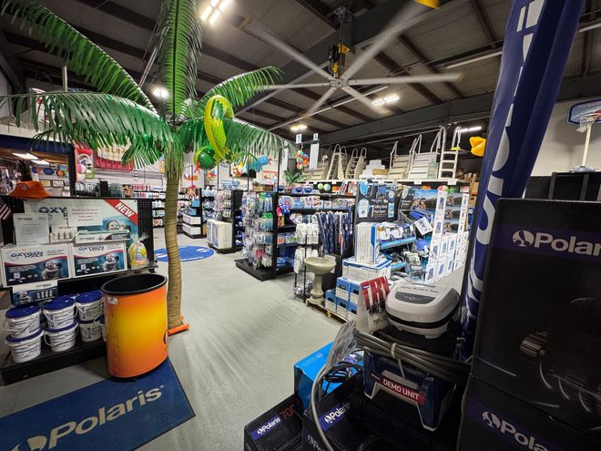 Kids jumping into a pool with inflatable toys on a sunny day.