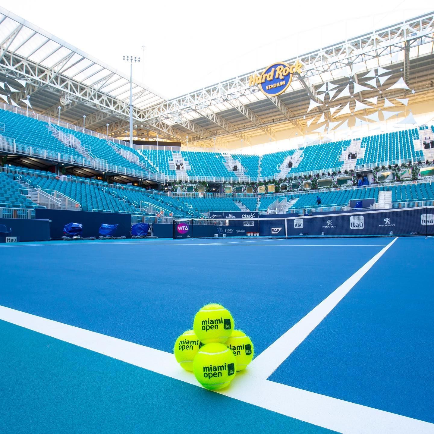 Three tennis balls on a blue court inside an empty stadium