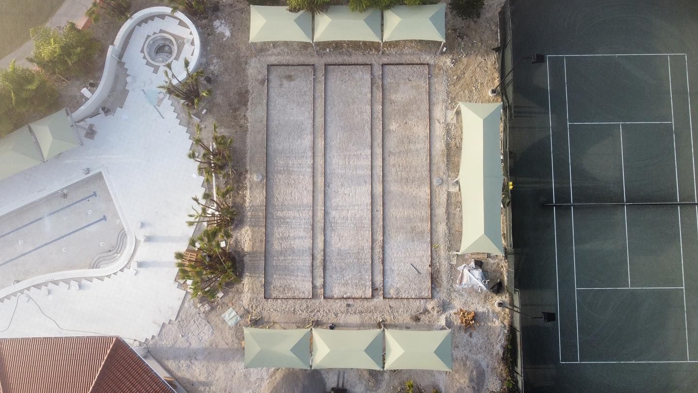 Aerial view of a rooftop courtyard with benches, potted plants, and a tennis court beside it.