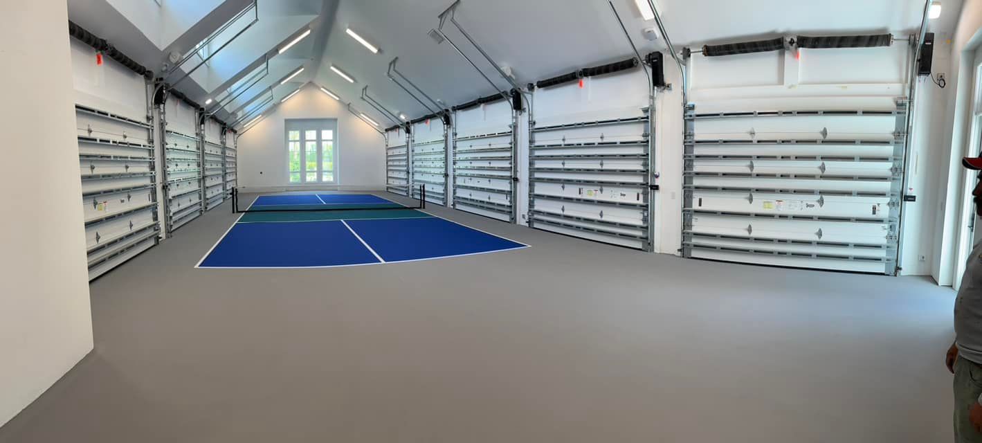 Empty indoor sports court with blue mats in a bright, white-walled gym room
