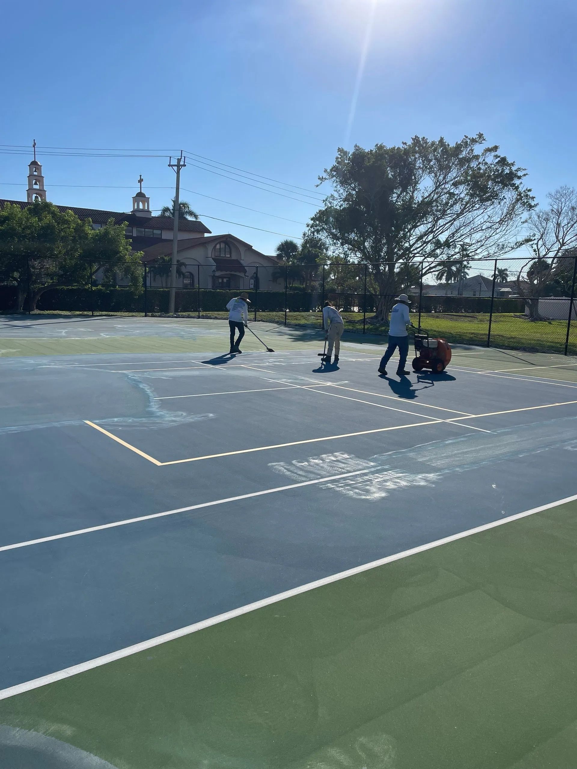People playing on a sunlit outdoor court with a city skyline in the background