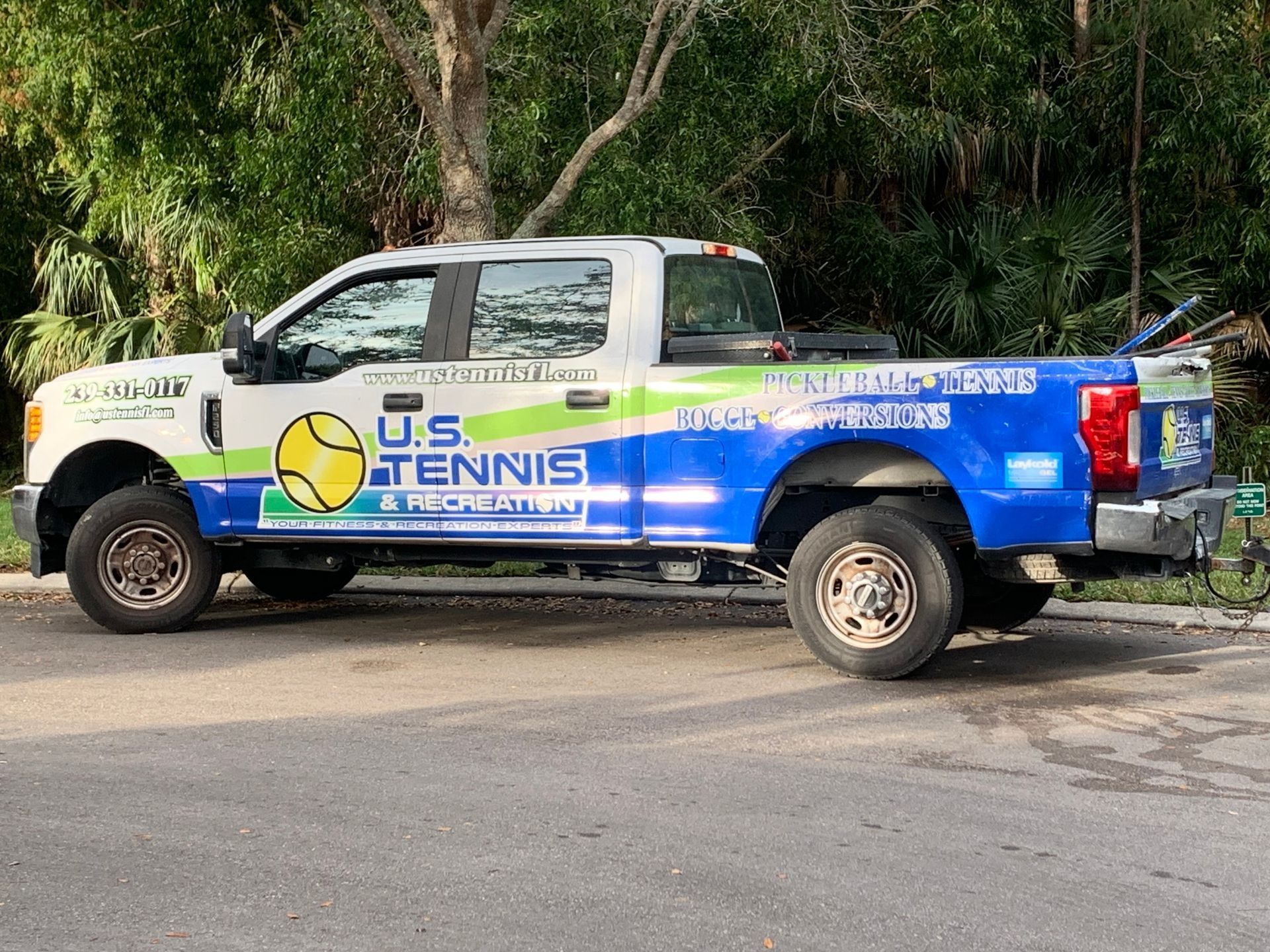 Blue U.S. Tennis van parked on the roadside with large logos and white cab.