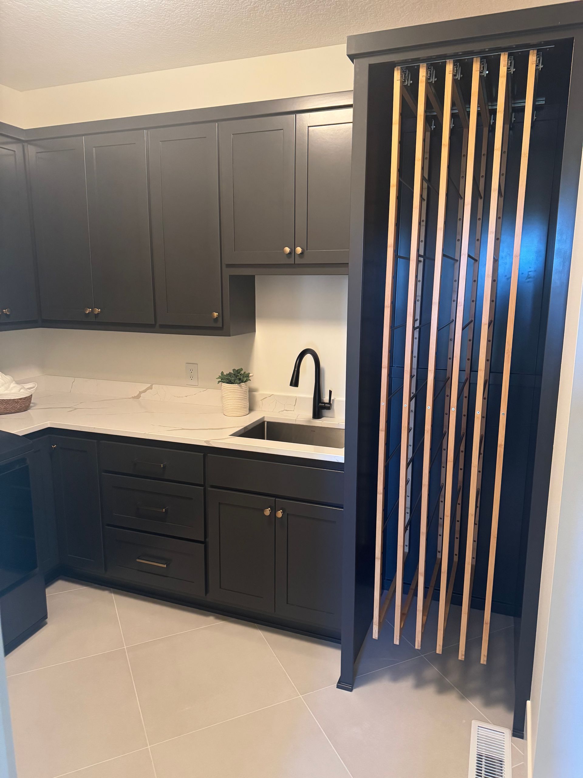 Modern kitchen with dark cabinets, white countertops, and vertical slatted room divider.