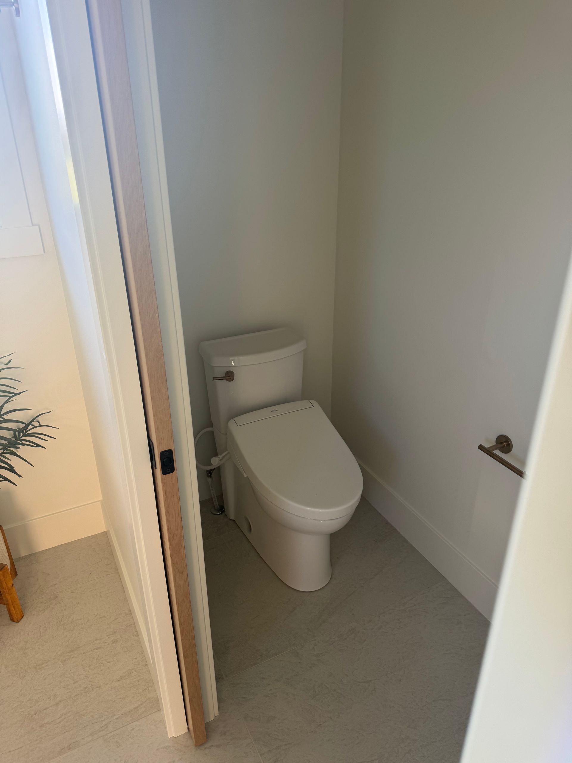 Small bathroom with a white toilet in a narrow alcove, viewed through an open doorway.