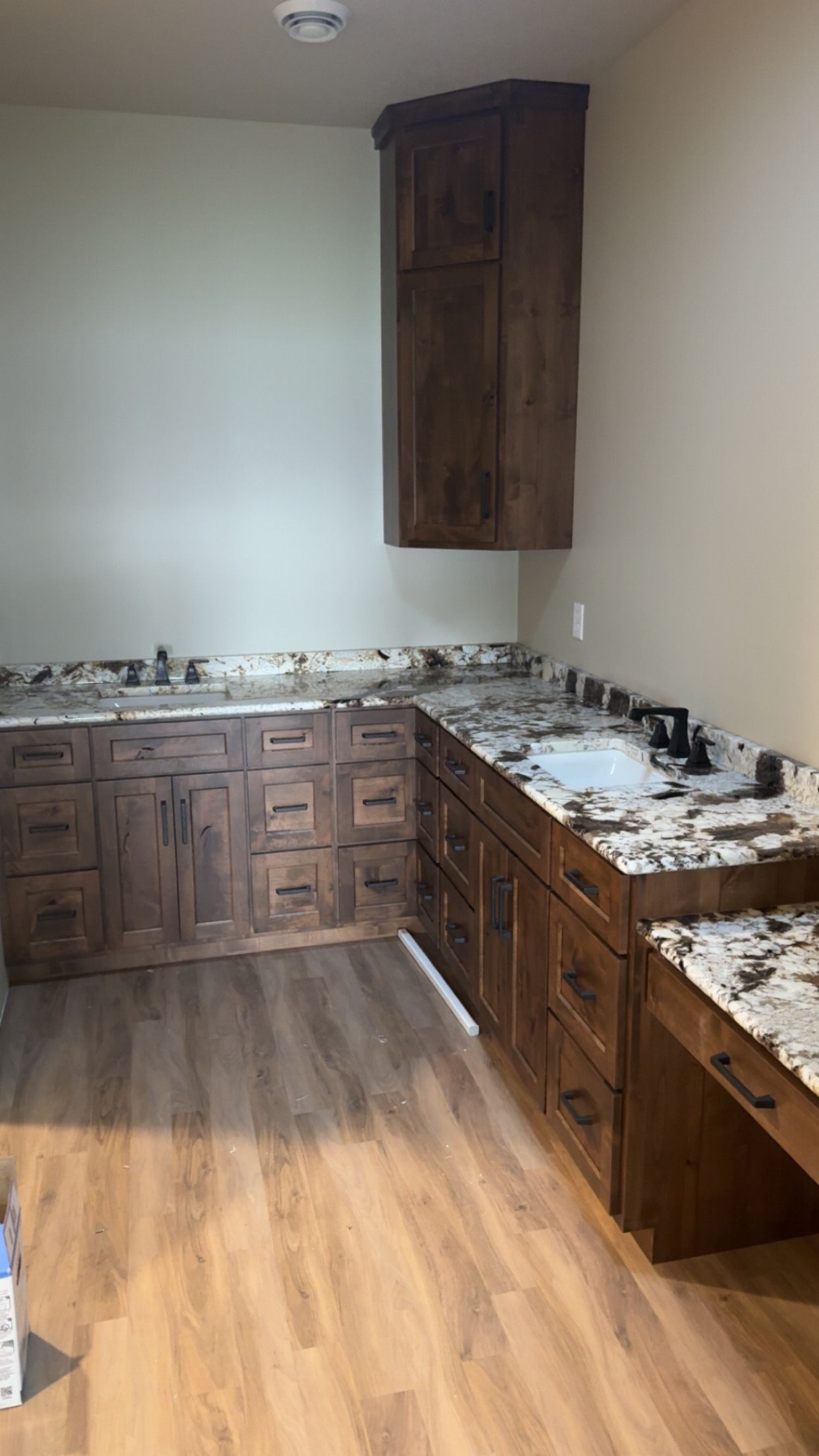Empty kitchen with dark wood cabinets, granite countertops, and hardwood floors.