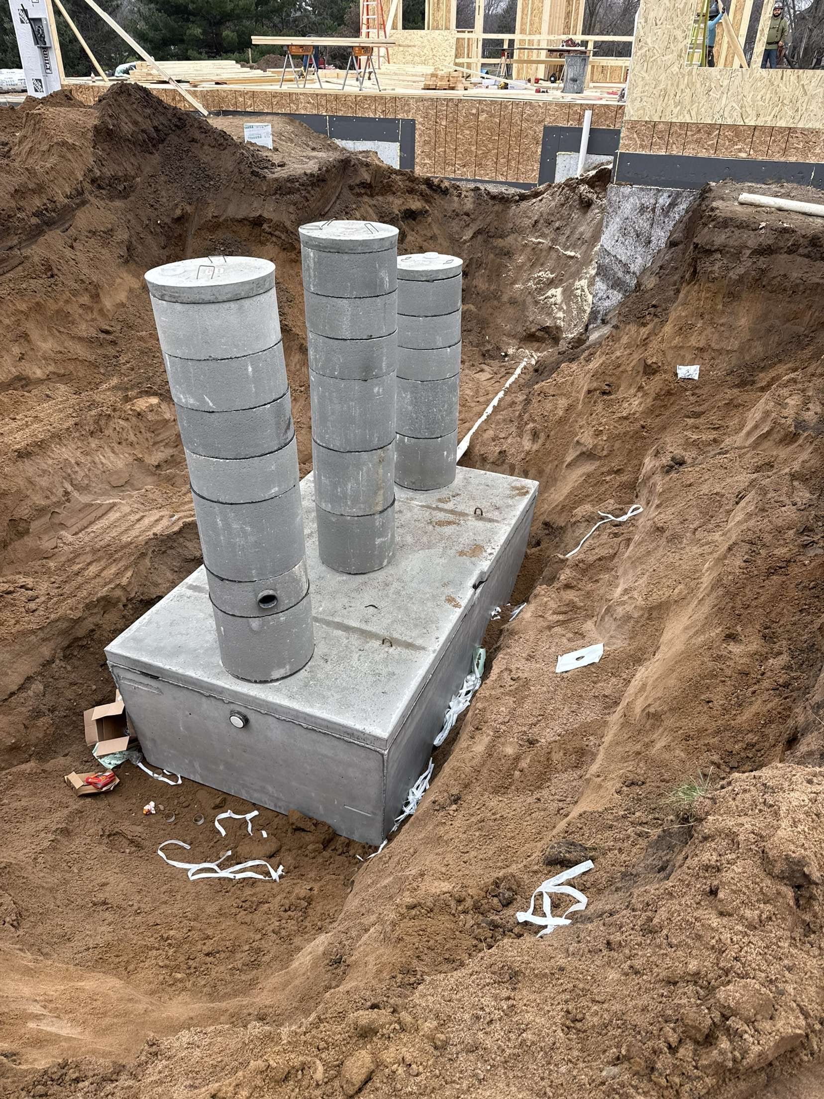 Concrete foundation with four gray cylindrical columns in an excavated dirt site.